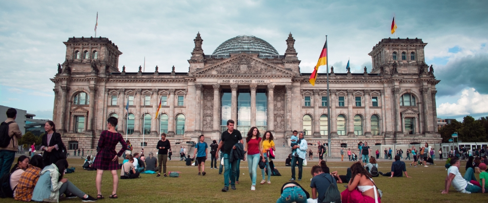 The Reichstag building in Berlin with its modern glass dome and the German flag flying at the entrance.